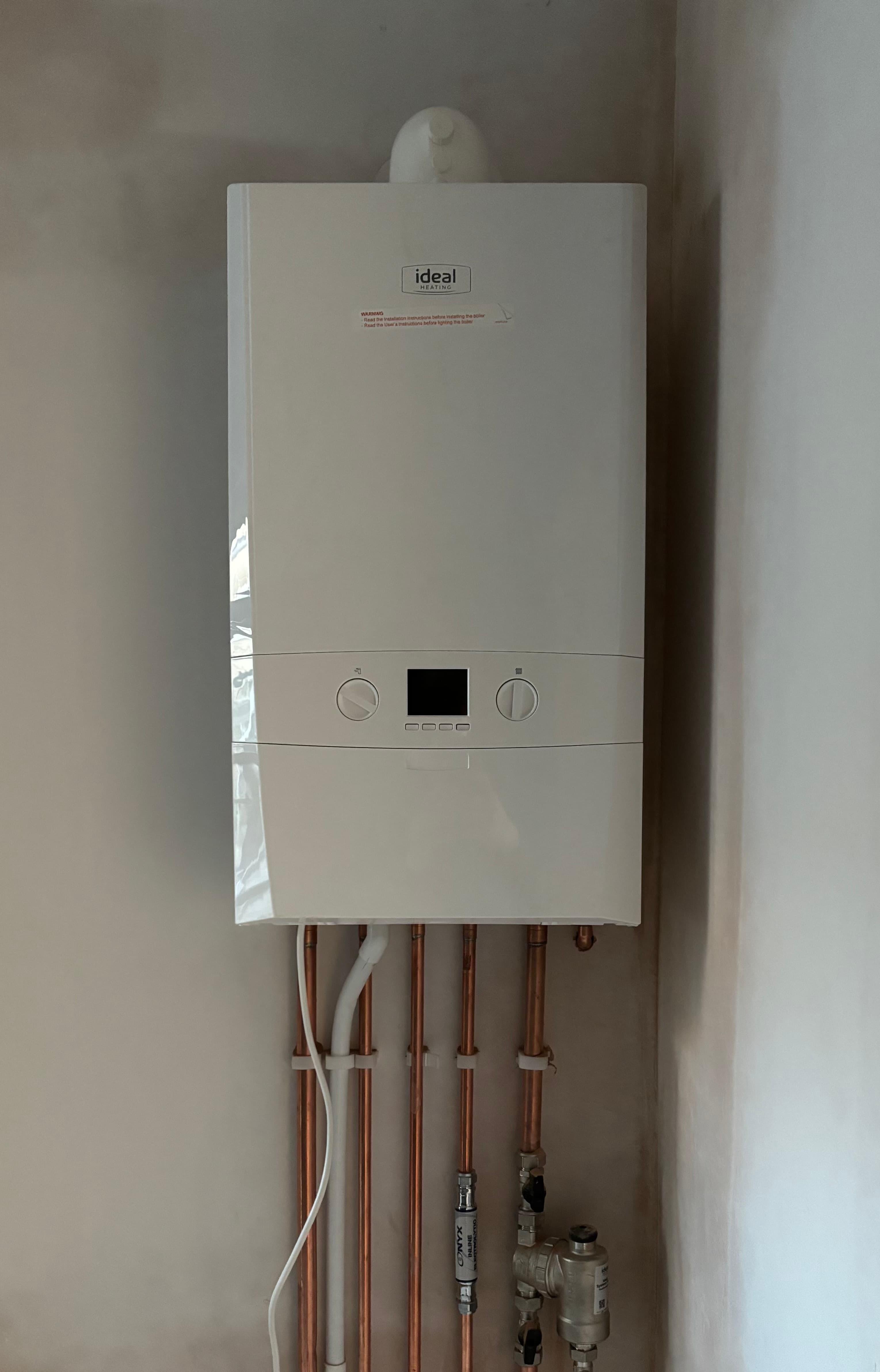 Wall-mounted Ideal boiler installation with exposed copper pipework.